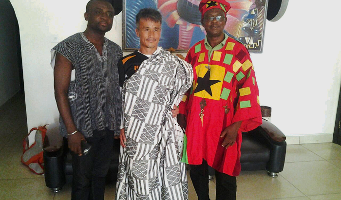 Kenichi poses in his kente gift. On his right is One Man Supporter One Man honours Kenichi
